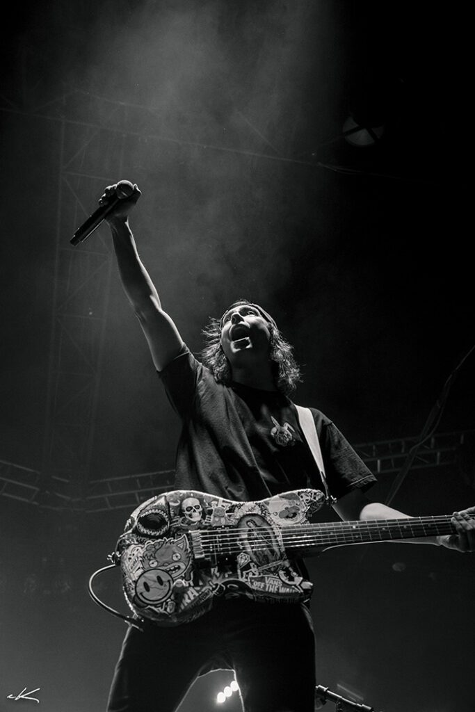 Musician performing energetically with guitar on stage.