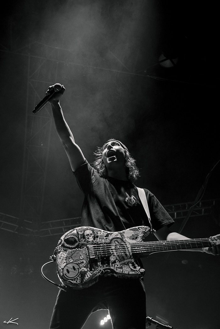 Musician performing energetically with guitar on stage.