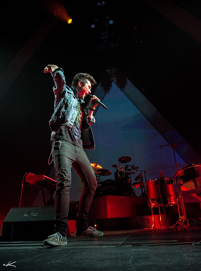 Singer performing energetically on stage with microphone.