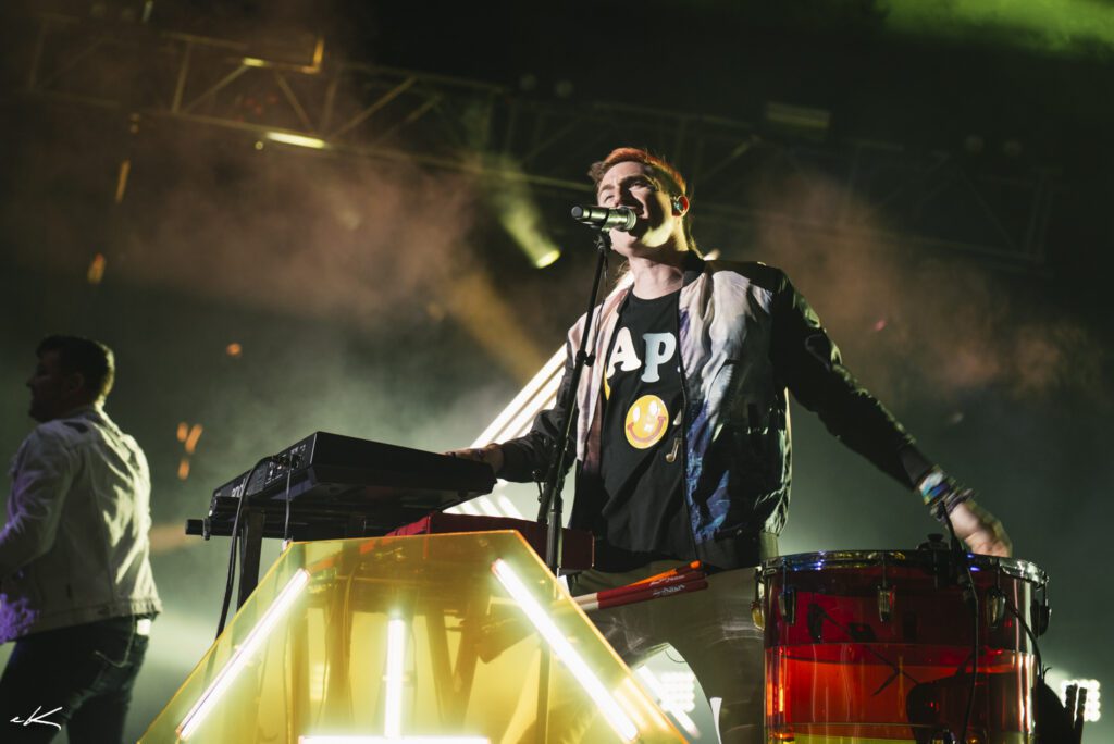 Musician performing energetically on stage with lights.