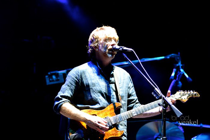Musician playing guitar and singing on stage.