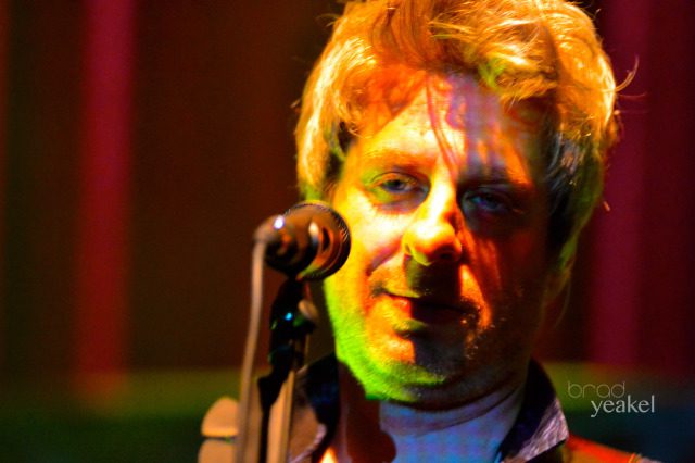 Musician singing on stage with microphone.