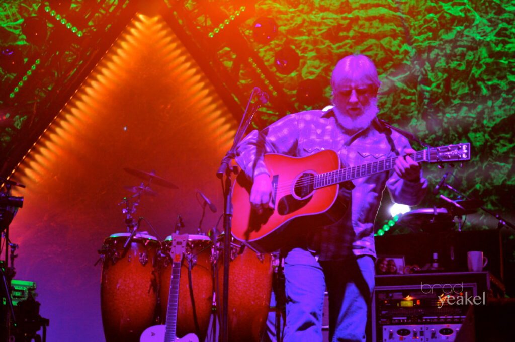 Musician playing guitar on colorful stage.