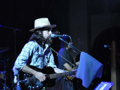 Musician performing on stage with guitar.