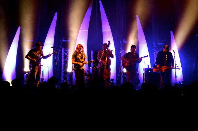 Band performing on stage with colorful lights.
