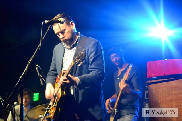 Musicians performing on stage with bright lights.