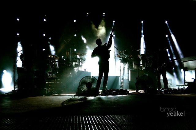 Silhouetted band performing on a dimly lit stage.