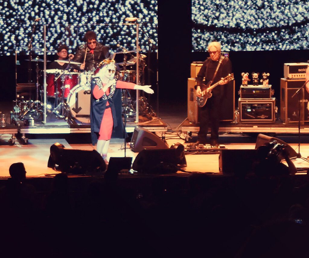 Band performing live on stage with instruments.