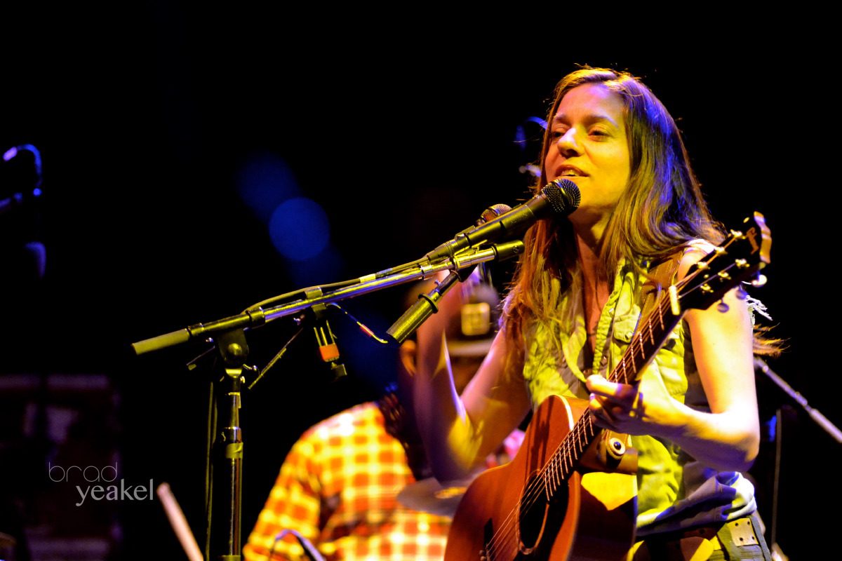 Singer performing with a guitar on stage.