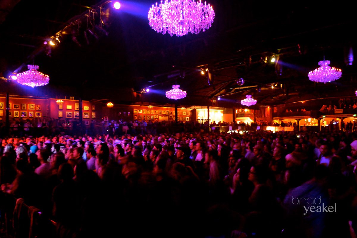 Concert crowd under purple-lit chandeliers.