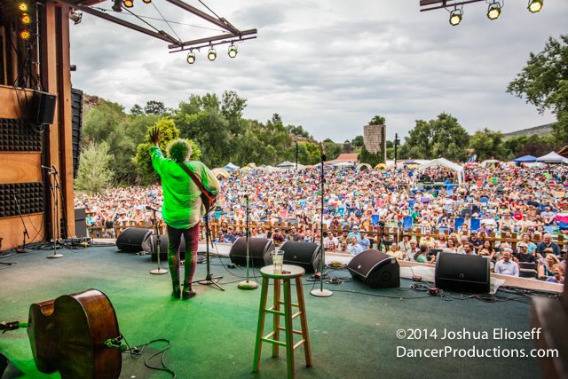 Musician performing on stage before large crowd.