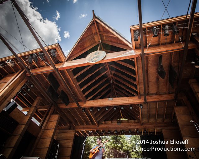 Wooden stage with performer under cloudy sky.