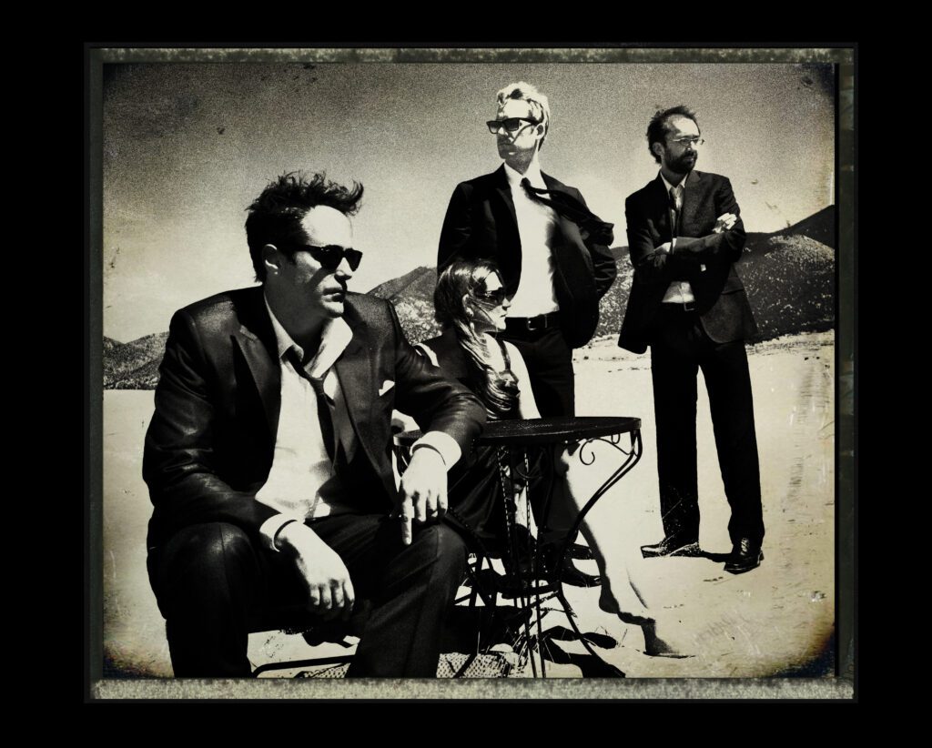 Four people in suits, outdoors, vintage style.