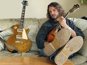 Man with mandolin, guitar on couch.