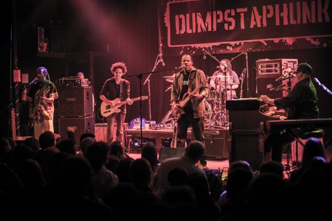 Band performing live on stage with instruments.
