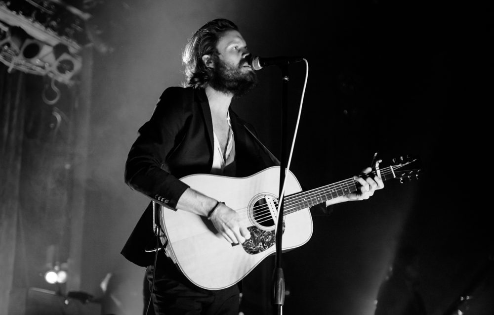 Musician performing on stage with guitar.