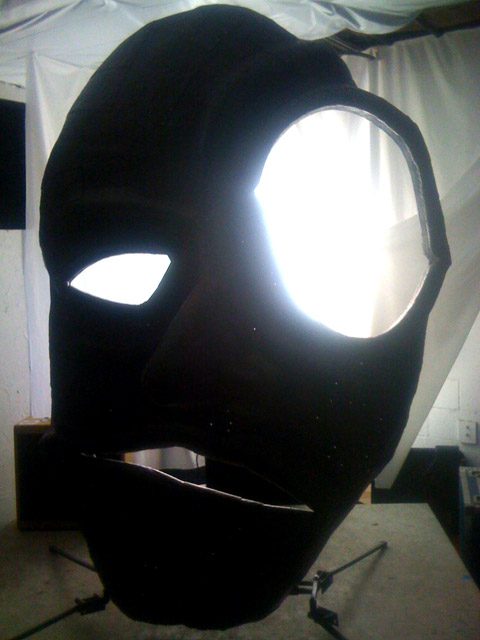 Large abstract mask sculpture with glowing eyes.