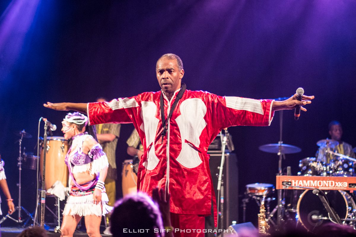 Performer in red robe on stage, dancing.