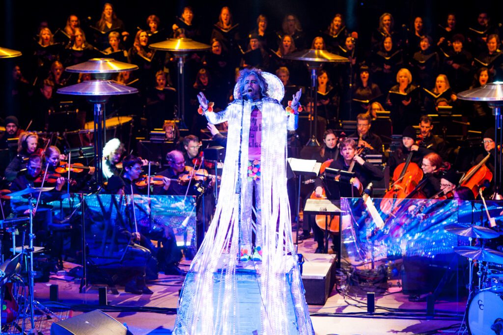 Performer onstage with orchestra and choir ensemble.