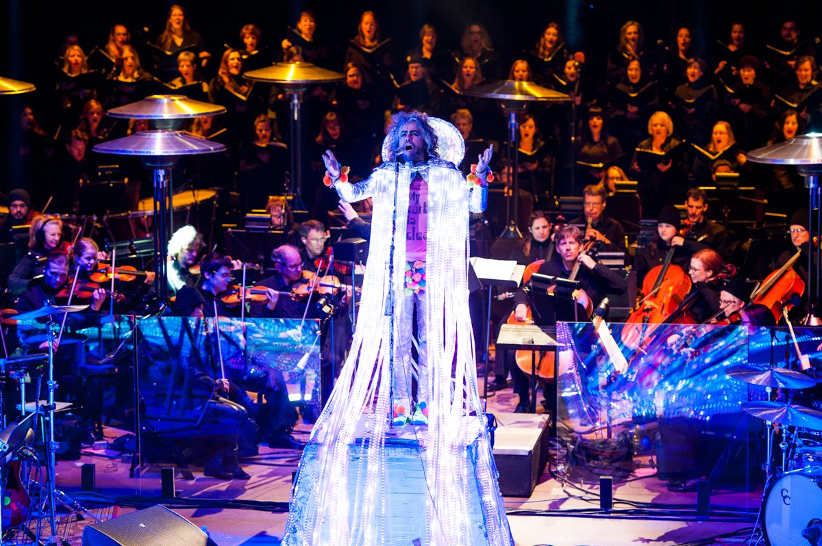 Performer onstage with orchestra and choir ensemble.