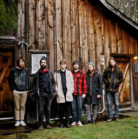 Six people standing in front of cabin.