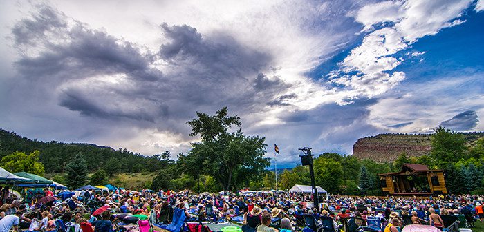 Outdoor festival crowd under dramatic cloudy sky.