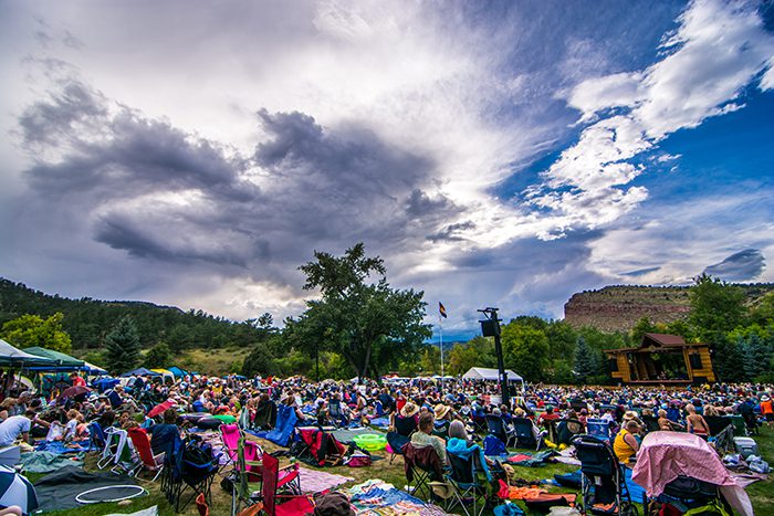 Outdoor festival crowd under dramatic cloudy sky.
