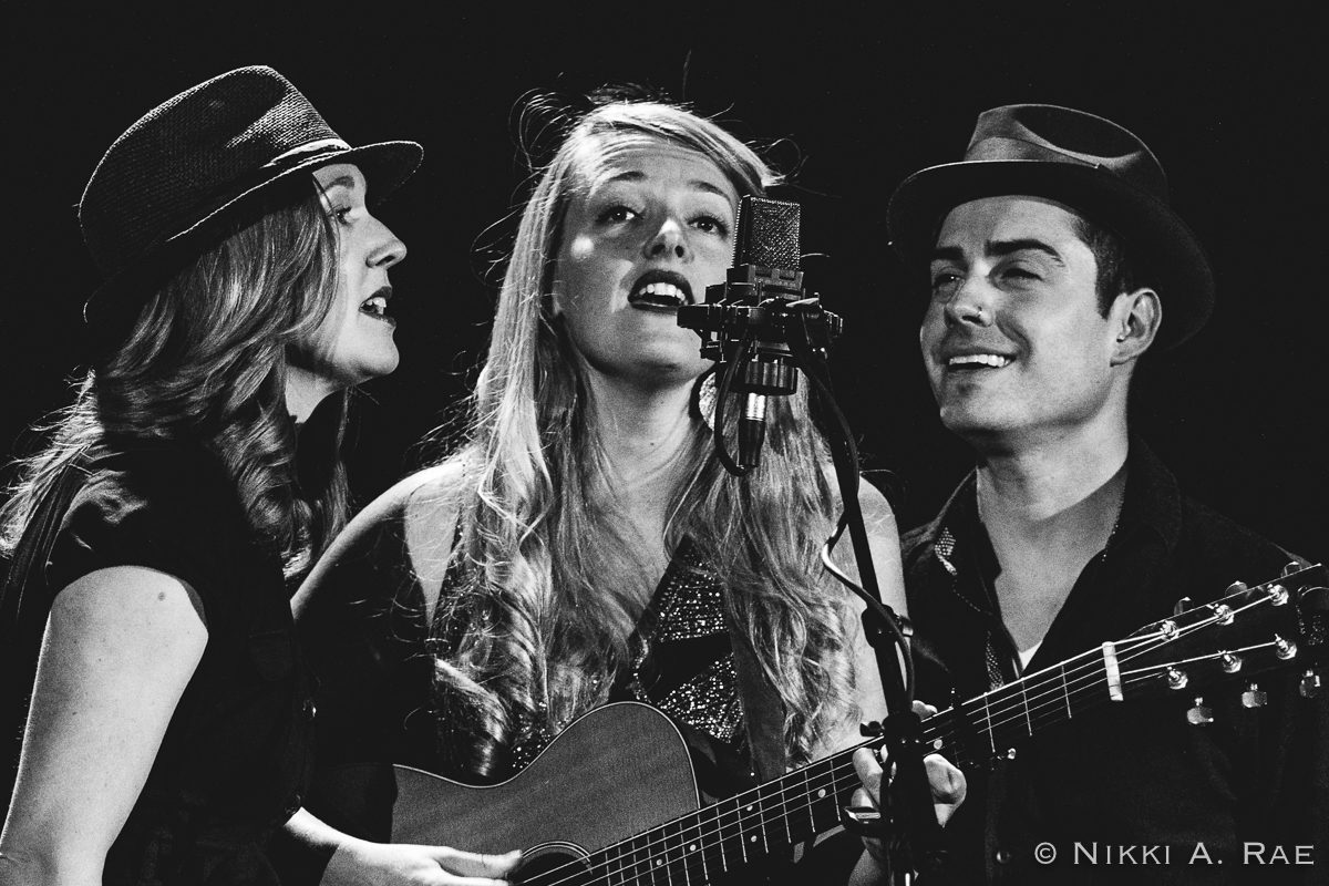 Trio singing with guitar and microphone.