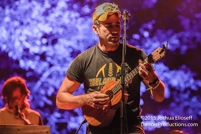 Musician playing guitar on vibrant stage.