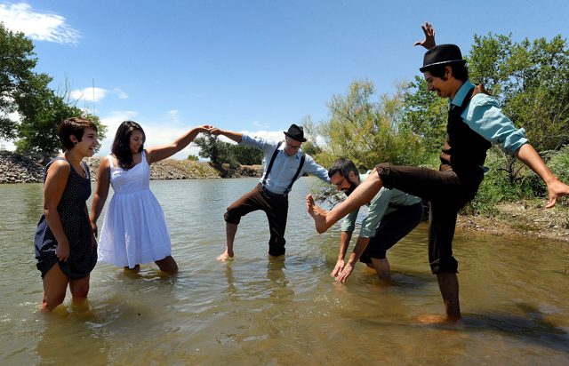 People dancing in a river, wearing hats.