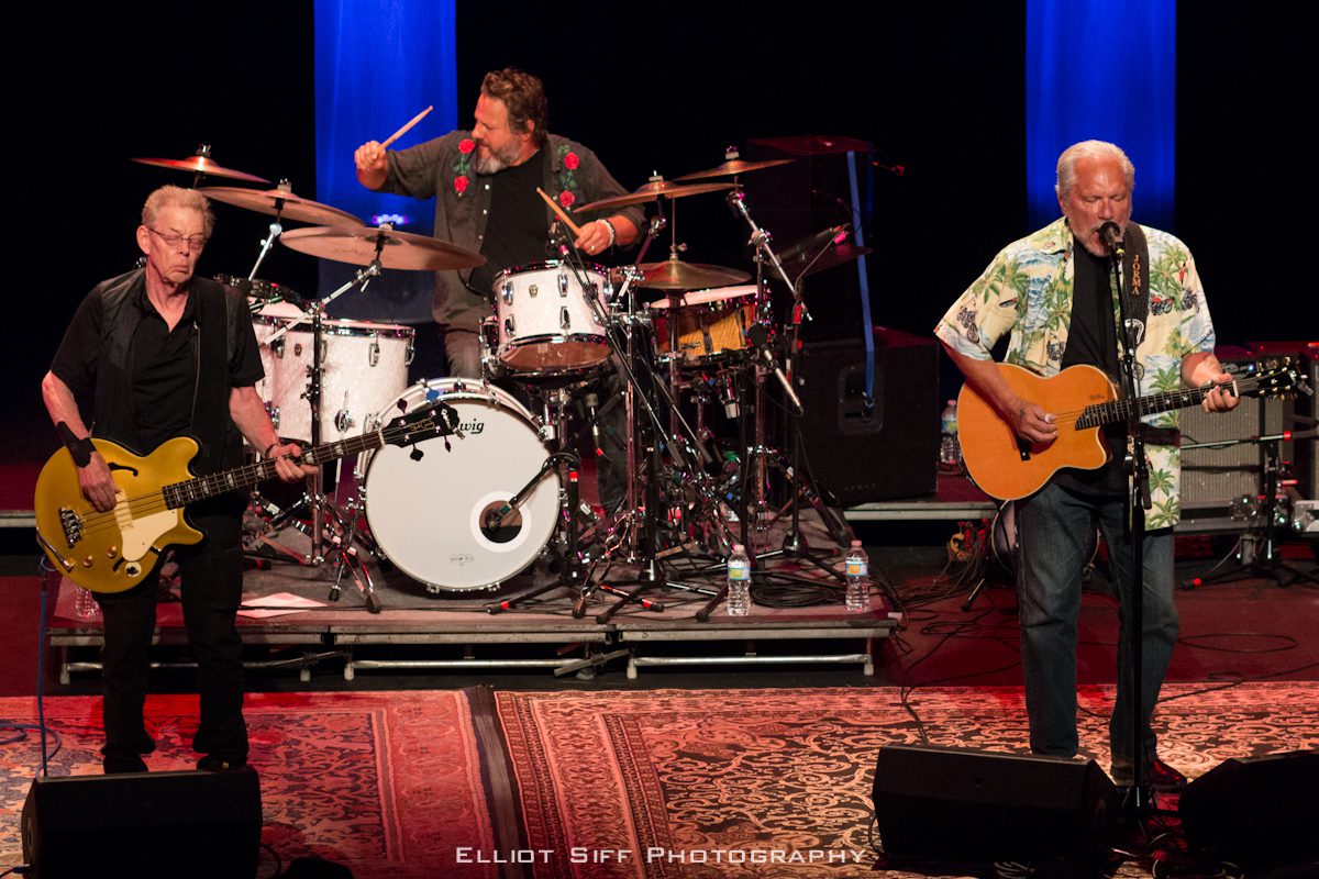 Three musicians performing live on stage.