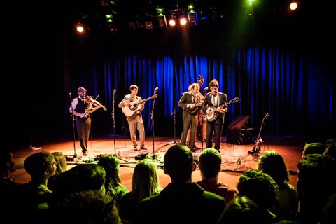 Band performing on stage with audience watching.