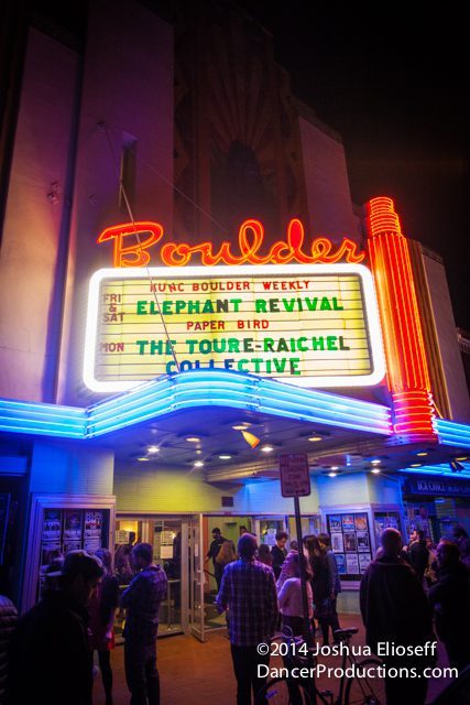 Neon-lit theater marquee with crowd outside.