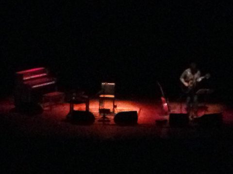Dimly lit stage with musician and instruments.