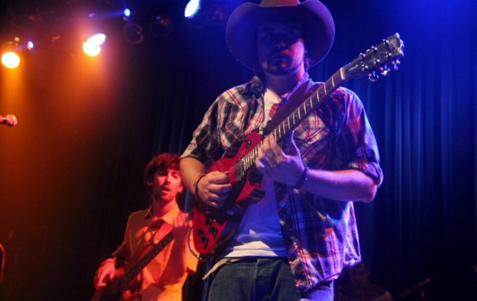 Musicians performing on stage with guitars.