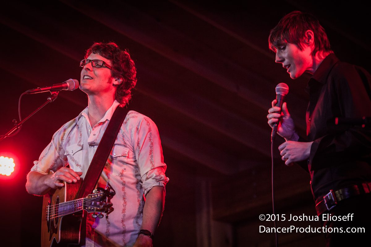 Two musicians performing on stage with microphones.