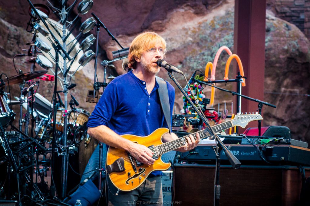 Musician performing with guitar on stage.