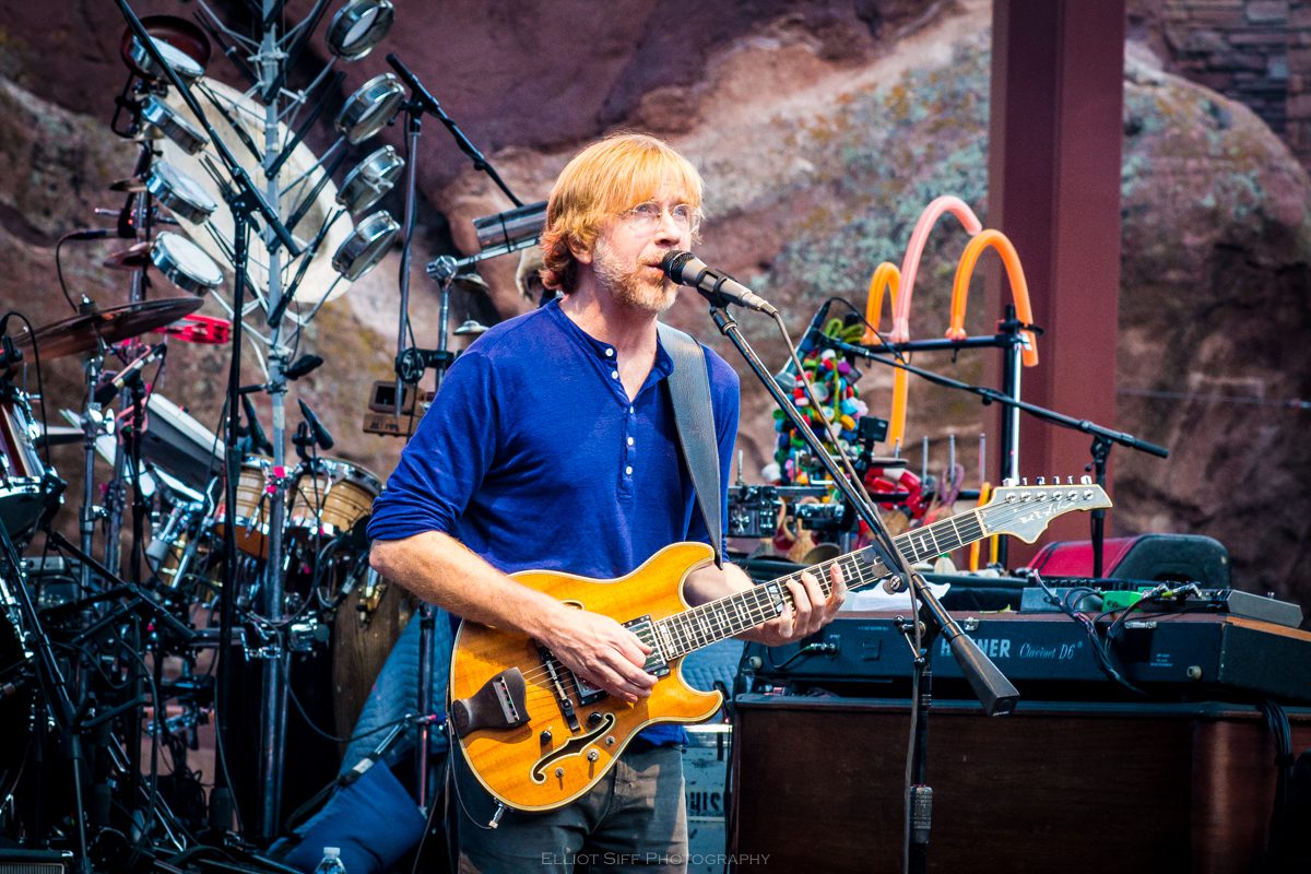 Musician performing with guitar on stage.