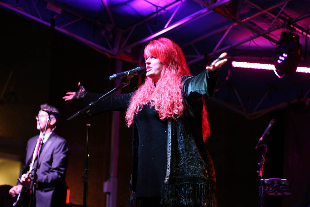 Singer performing on stage with guitarist.