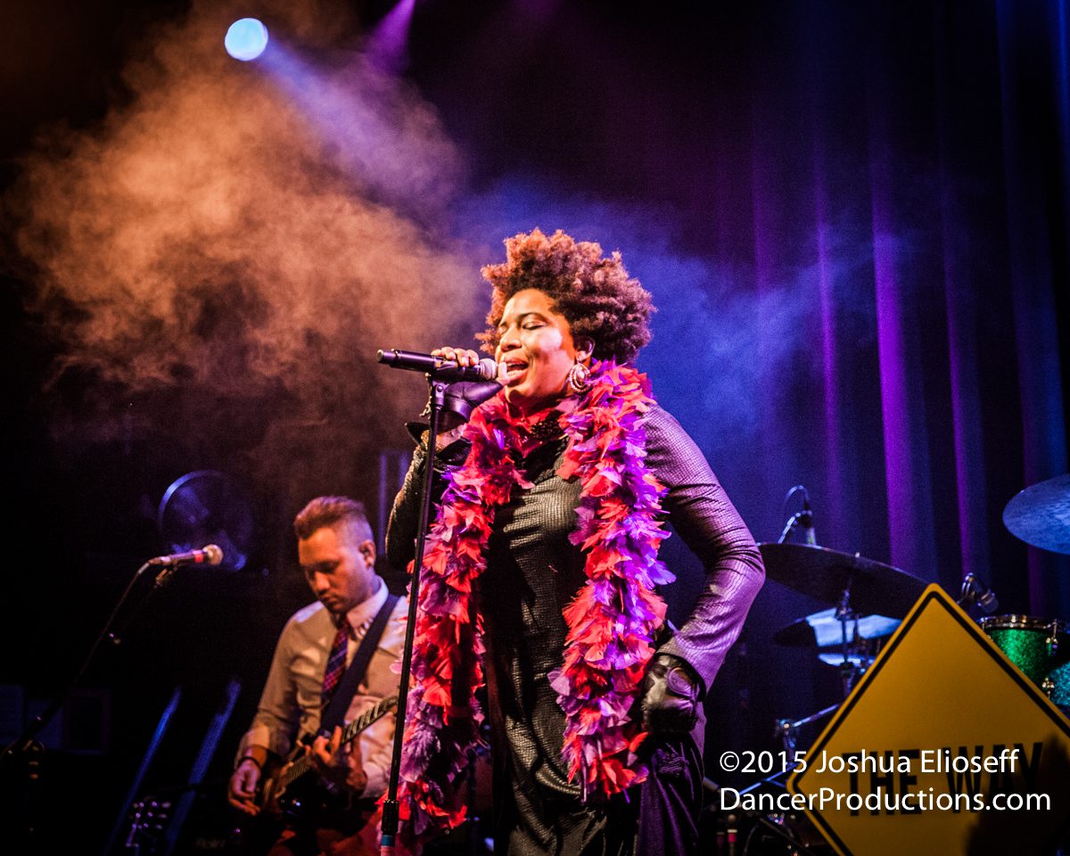 Singer performing energetically on stage with band.