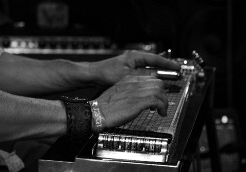 Hands playing a pedal steel guitar.