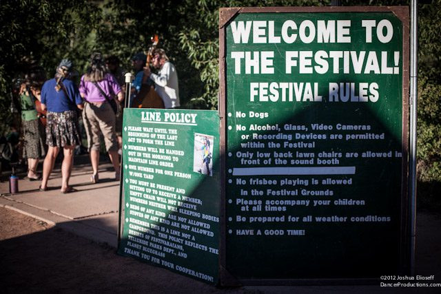 Festival rules sign with people in background.