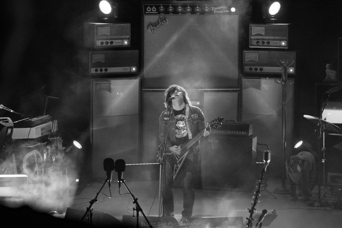 Guitarist performing live on stage with amplifiers.