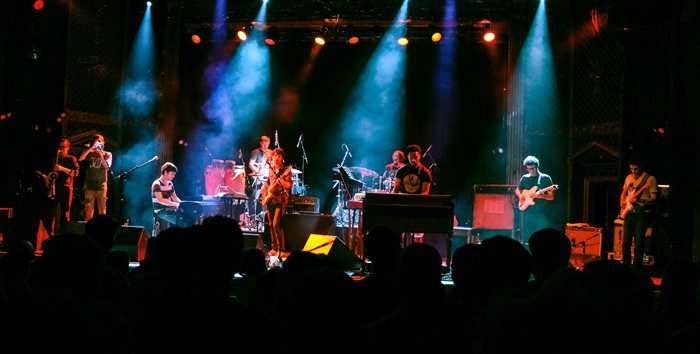 Live band performing on stage with lights.