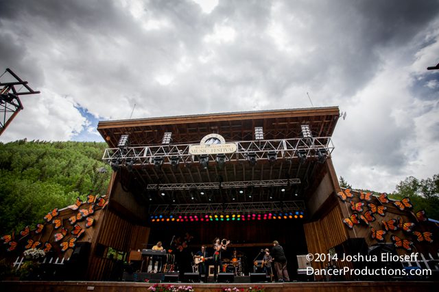 Outdoor concert stage with cloudy sky backdrop.