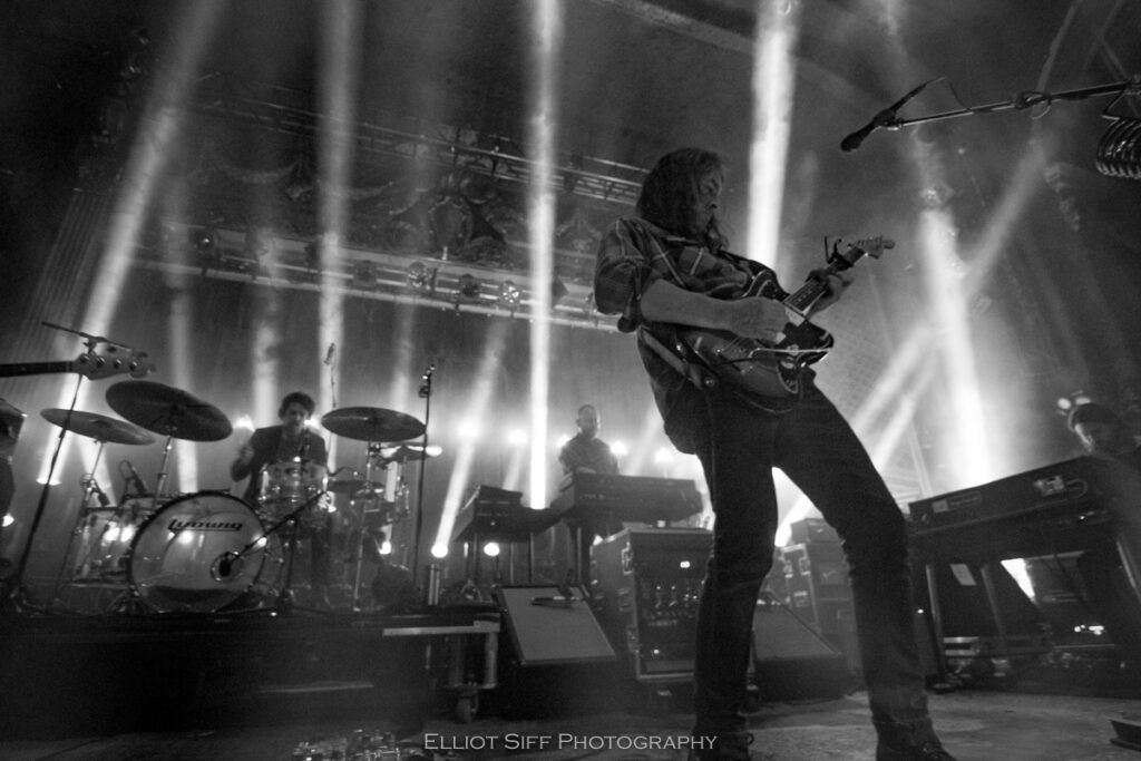 Band performing live with dramatic lighting effects.