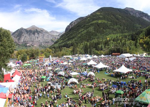 Outdoor festival with tents and mountain backdrop.