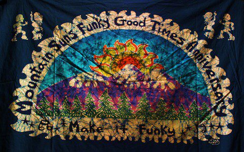 Tie-dye tapestry with sun and trees.