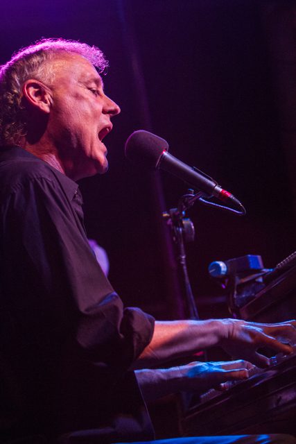 Man singing and playing piano on stage.