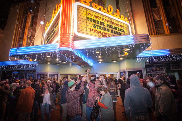 Crowd gathered outside illuminated theater marquee.